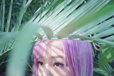 Close-up of young woman with dyed hair seen through plants