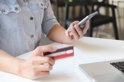 Midsection of man using mobile phone on table