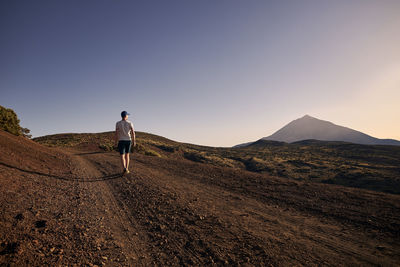 Rear view of man on mountain against sky