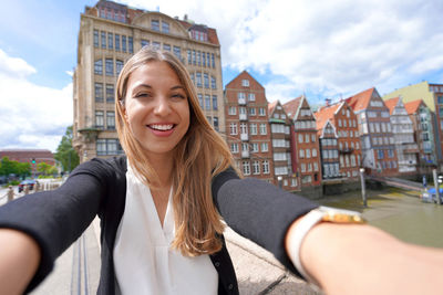 Portrait of young woman standing against buildings