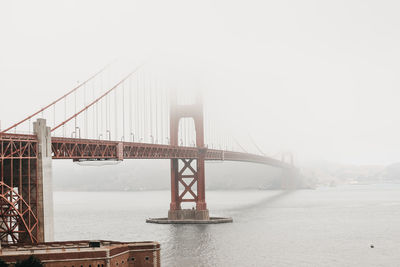 Suspension bridge over river during foggy weather