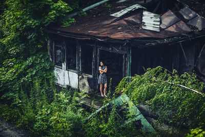 Young woman standing by plants in forest