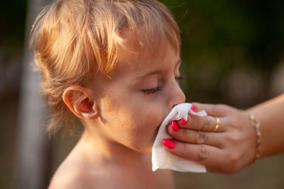 Cropped hand of mother wiping mouth of son 