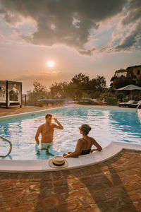Couple relaxing in swimming pool against sky