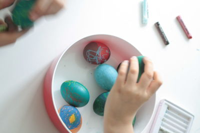 Cropped image of hand holding painted eggs on table