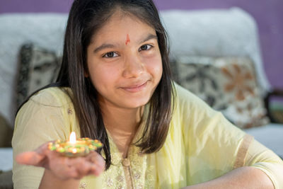 Portrait of a girl smiling while holding diya on the festive occasion of diwali