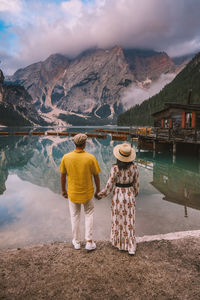 Rear view of woman looking at lake against mountain range