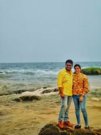Full length portrait of friends standing on beach