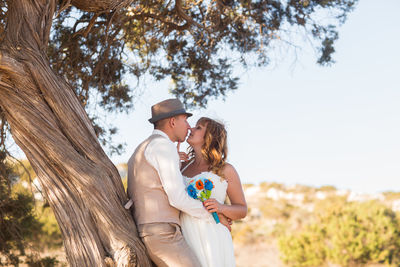 Couple standing by tree against plants