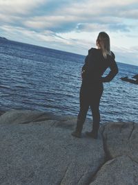 Rear view of woman standing on beach against sky