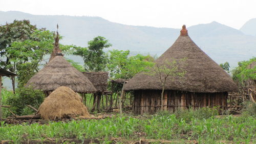 Wooden house on field by mountains against sky