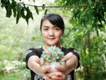 Portrait of young woman holding plants