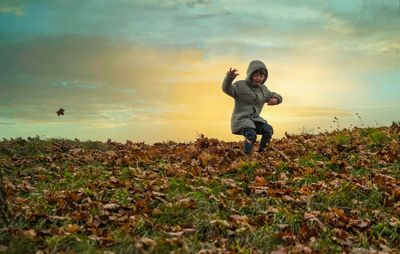 Full length of man and leaves on field against sky during sunset