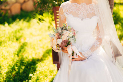 Midsection of woman holding bouquet of white flower