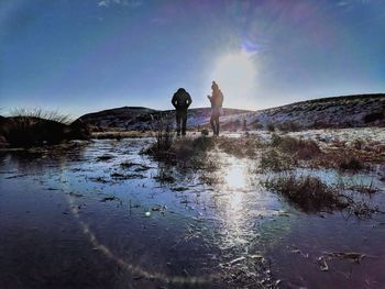 People standing on water against sky