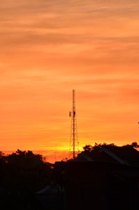 Low angle view of communications tower against orange sky