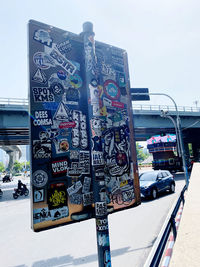 Information sign on road in city against sky