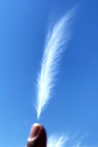 Low angle view of hand against blue sky