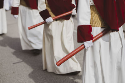 Midsection of people holding umbrella