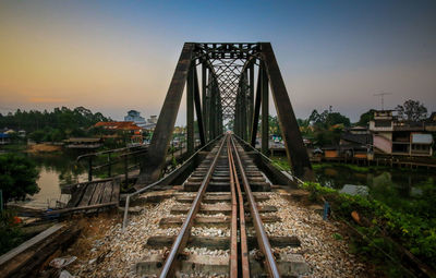 Railway bridge over river against sky during sunset