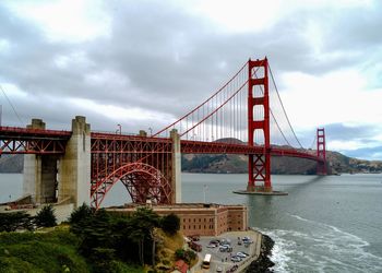 Golden gate bridge over river against cloudy sky