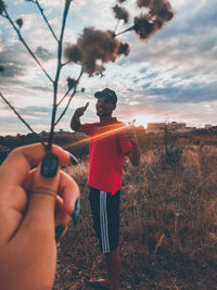 Midsection of man holding umbrella while standing on field against sky