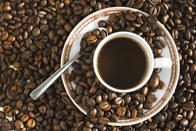 High angle view of coffee cup on roasted beans