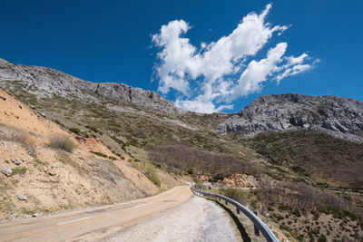 Panoramic view of road amidst mountains against blue sky