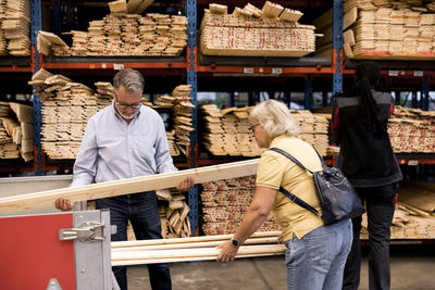 Senior customers examining and loading planks in trailer while shopping at hardware store