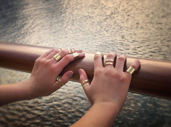 Cropped hands on woman on railing against sea