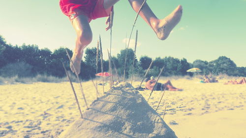 Low section of person on sand against sky