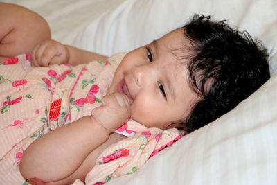 Close-up of baby girl smiling on bed