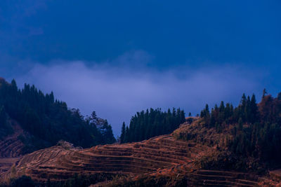 Panoramic view of trees and mountains against blue sky