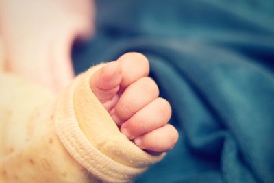 Cropped hand of baby on bed