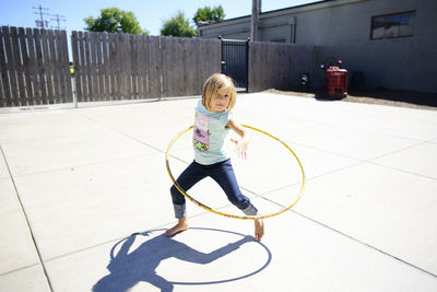 Portrait of girl playing with hula hoop at playground during summer