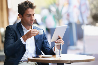 Businessman holding coffee cup looking at digital tablet