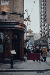 People walking on street amidst buildings in city