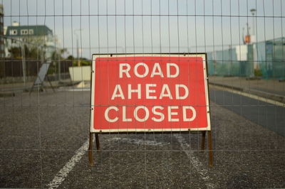 Road closed sign behind fence on street