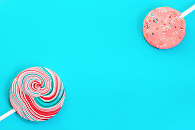 Two round colored pink and blue candy on a vintage turquoise background with space for copy.