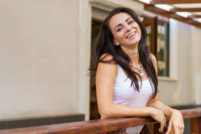 Portrait of smiling young woman standing against wall
