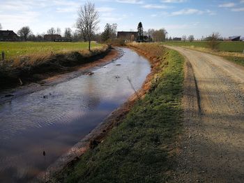 Road by canal against sky