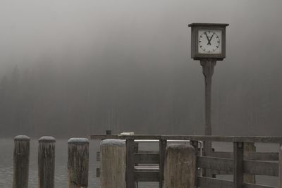 Low angle view of clock on wooden post against sky