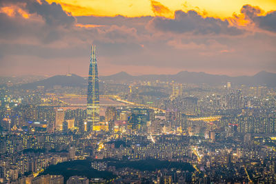 Illuminated cityscape against sky during sunset