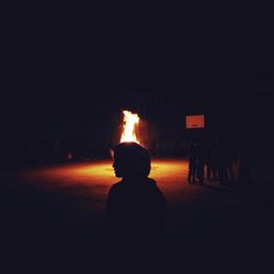 Rear view of silhouette people against fire at night