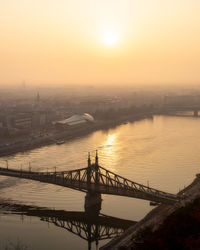 Bridge over river against sky during sunset