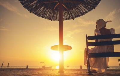 Traditional windmill on beach against sky during sunset