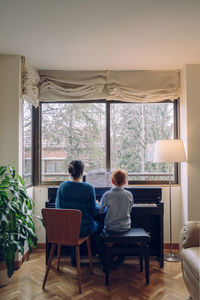 Rear view of people sitting on table at home