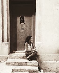 Thoughtful woman sitting on steps against wall