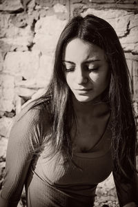 Teenage girl looking down while sitting against wall