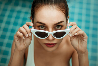 High angle portrait of young woman wearing sunglasses in swimming pool